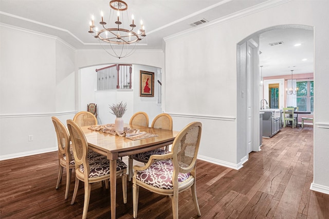 dining area with visible vents, crown molding, a chandelier, hardwood / wood-style flooring, and arched walkways
