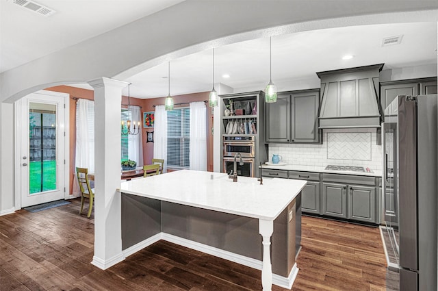 kitchen with visible vents, custom exhaust hood, gray cabinets, arched walkways, and stainless steel appliances