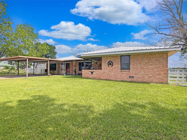 back of property with fence, a yard, metal roof, and brick siding