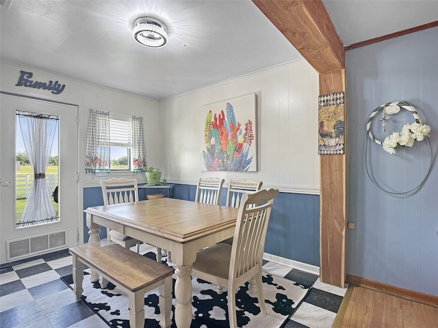 dining area with crown molding, visible vents, and a decorative wall