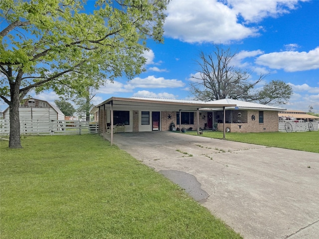 single story home featuring a front yard, a carport, brick siding, fence, and concrete driveway