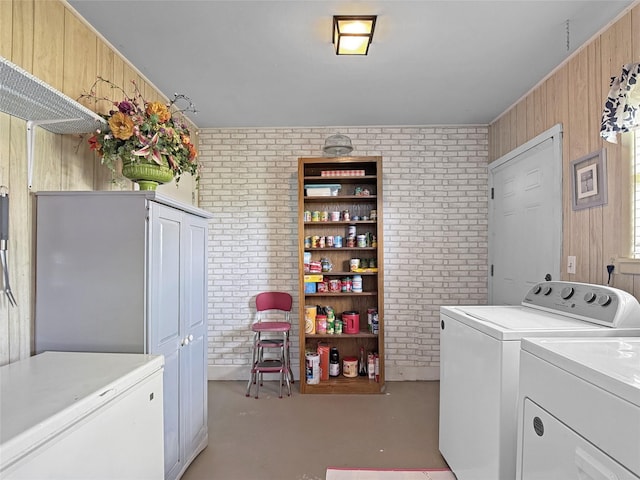 laundry room with washer and dryer, laundry area, wood walls, and brick wall