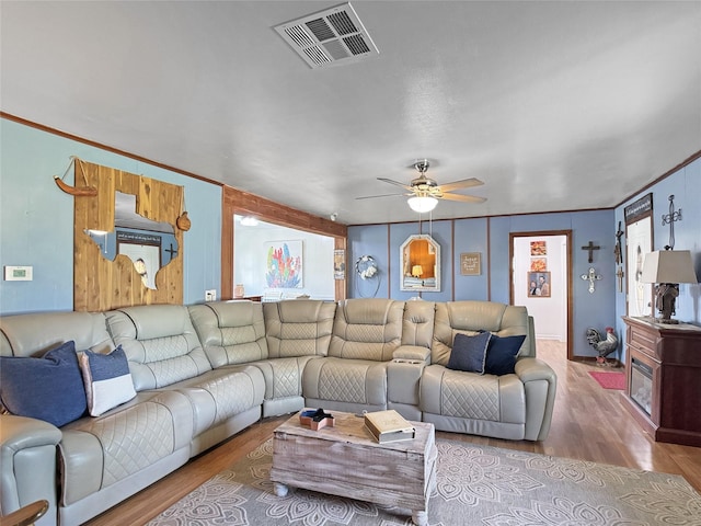 living area featuring ceiling fan, visible vents, ornamental molding, and wood finished floors