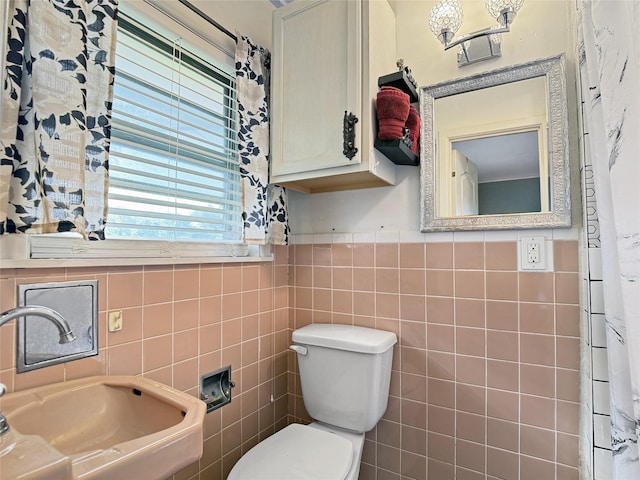 bathroom featuring a sink, tile walls, and toilet