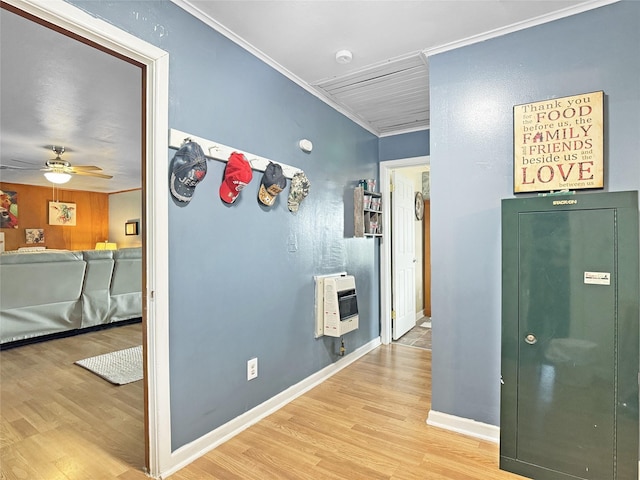 corridor featuring light wood-style floors, baseboards, heating unit, and crown molding