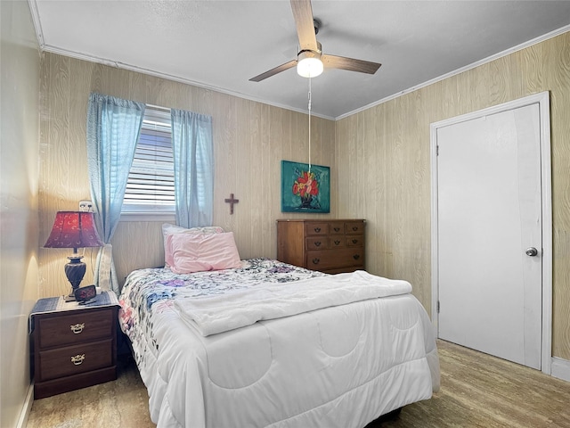 bedroom with crown molding, a ceiling fan, and wood finished floors