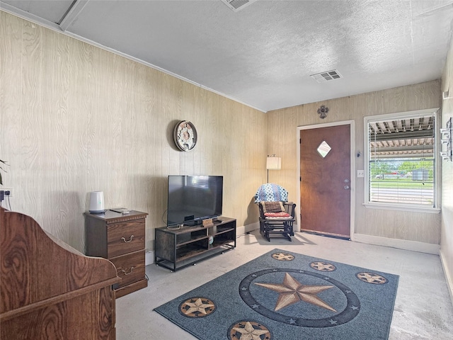 living area featuring baseboards, a textured ceiling, and visible vents