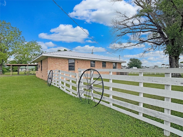 view of side of home with fence, a lawn, metal roof, and brick siding