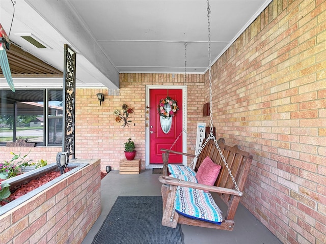 property entrance featuring covered porch and brick siding