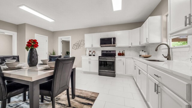10018 Jackson Rd, Krum, TX 76249 - kitchen with white cabinetry, appliances with stainless steel finishes, a sink, and tasteful backsplash