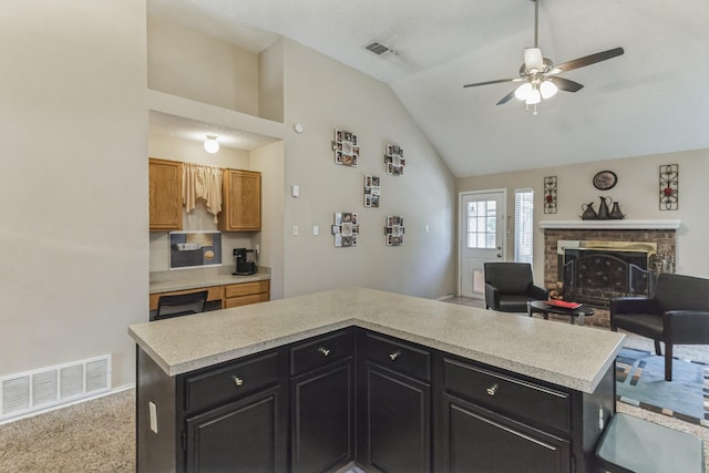 kitchen featuring visible vents, light countertops, a brick fireplace, and dark cabinets
