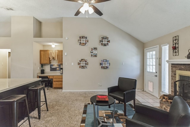 living room featuring ceiling fan, a brick fireplace, baseboards, lofted ceiling, and visible vents