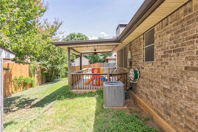 view of yard with a fenced backyard, ceiling fan, and central AC