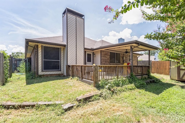 rear view of house featuring ceiling fan, a chimney, a lawn, a deck, and a fenced backyard