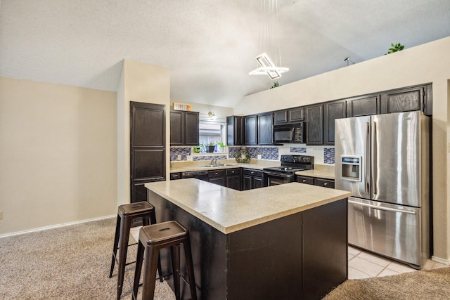 kitchen with a center island, light countertops, a sink, black appliances, and vaulted ceiling