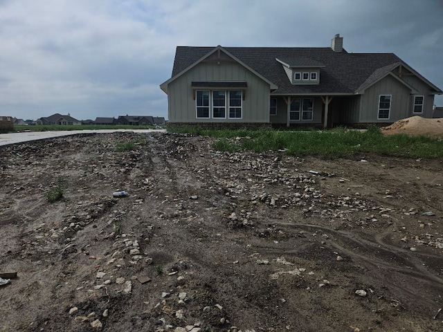 view of front of home with board and batten siding, a chimney, and roof with shingles