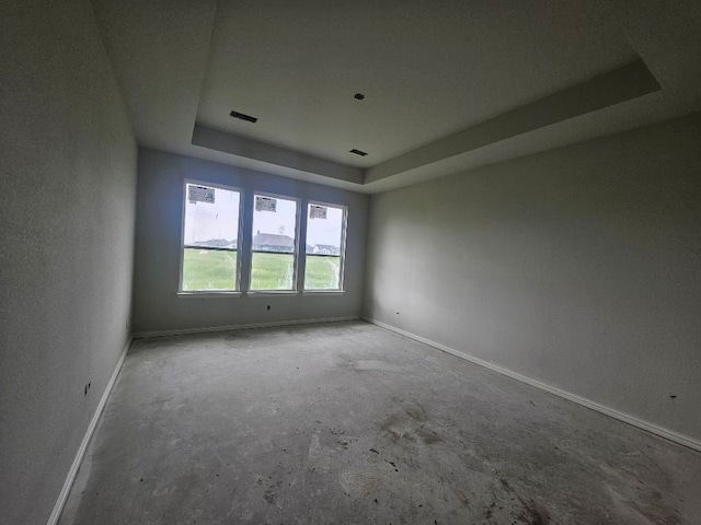 unfurnished room with baseboards, a tray ceiling, and visible vents