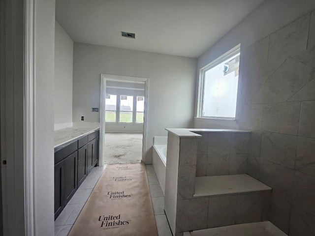 bathroom featuring vanity, plenty of natural light, a bath, and visible vents