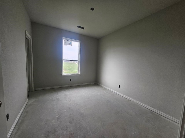 empty room with unfinished concrete floors, baseboards, and visible vents