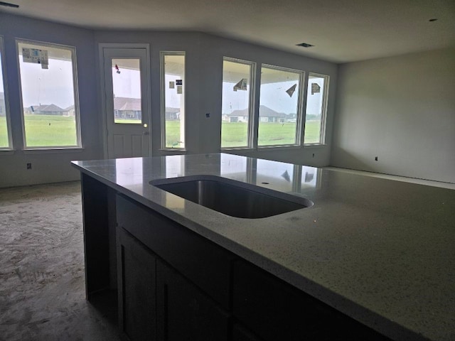 kitchen with light stone counters, carpet flooring, and a sink