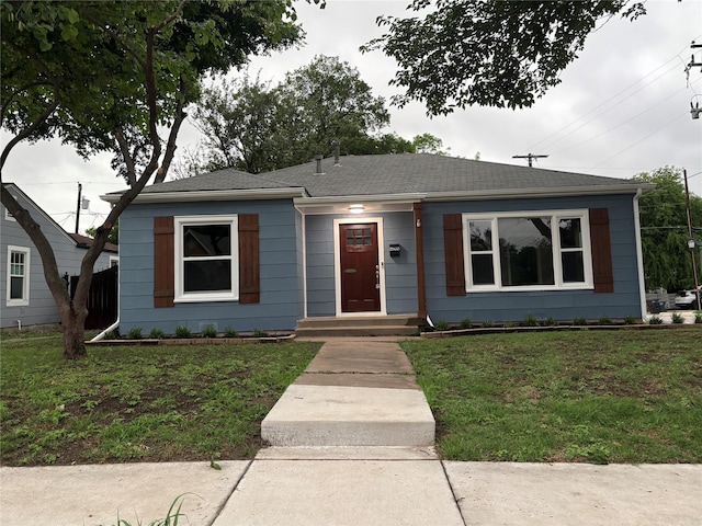 view of front of property featuring a shingled roof and a front lawn