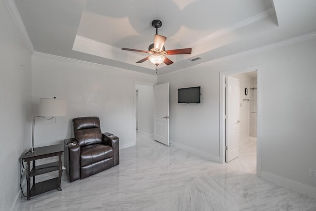 sitting room with a raised ceiling, a ceiling fan, marble finish flooring, ornamental molding, and baseboards