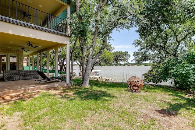 view of yard with a ceiling fan, a patio area, a balcony, and a water view
