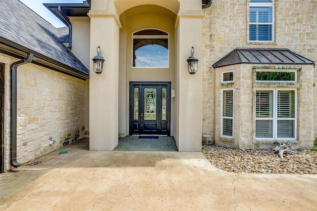 entrance to property with a standing seam roof, stone siding, and stucco siding