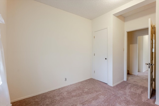 unfurnished bedroom featuring a textured ceiling, light carpet, and baseboards