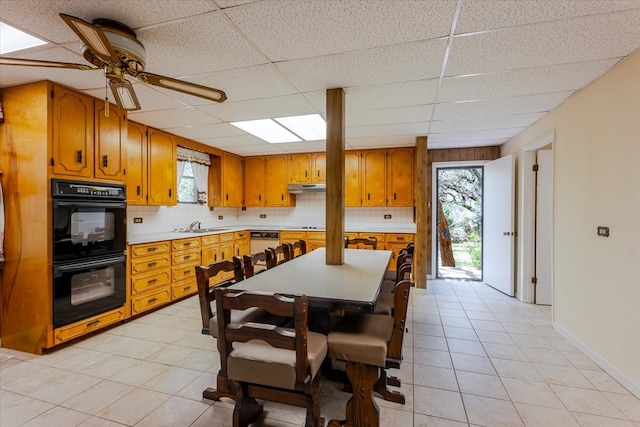 dining area featuring baseboards, a ceiling fan, a drop ceiling, and light tile patterned flooring