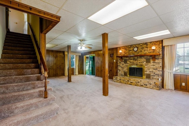 basement with stairs, wood walls, carpet, and a drop ceiling