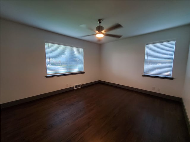 unfurnished room with baseboards, ceiling fan, dark wood-style flooring, and visible vents