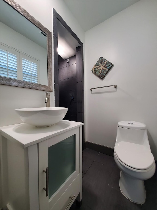bathroom featuring toilet, baseboards, and vanity