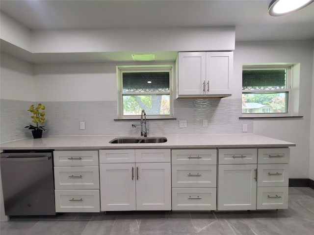 kitchen with dishwasher, light countertops, white cabinetry, a sink, and backsplash
