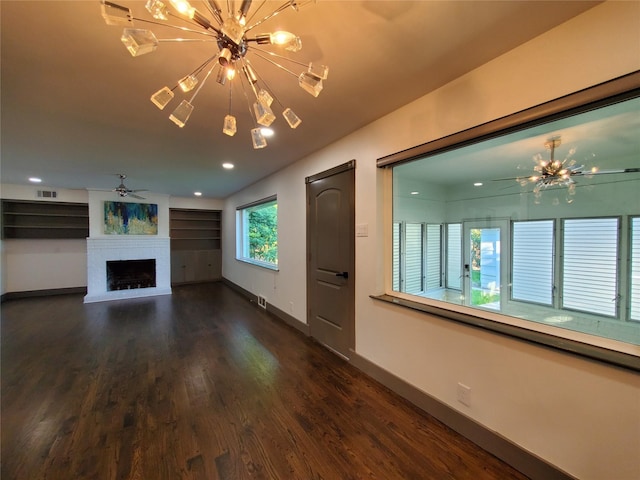 unfurnished living room with visible vents, wood finished floors, a fireplace, baseboards, and ceiling fan with notable chandelier