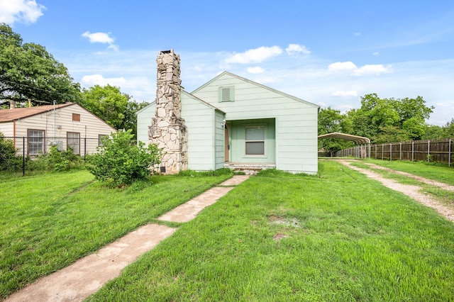back of house featuring a lawn, fence, driveway, and a carport