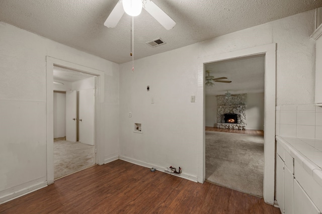 interior space featuring visible vents, ceiling fan, wood finished floors, and a stone fireplace