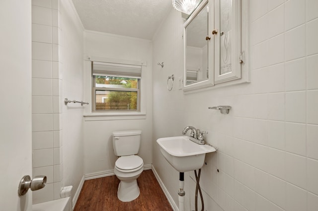 bathroom with a textured ceiling, toilet, and wood finished floors
