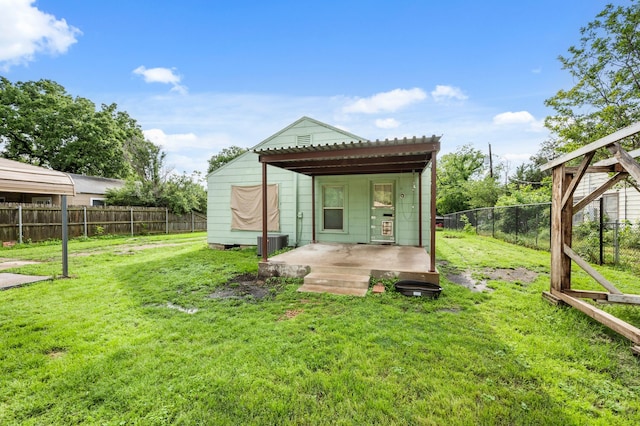 rear view of house featuring a fenced backyard, a lawn, and central AC
