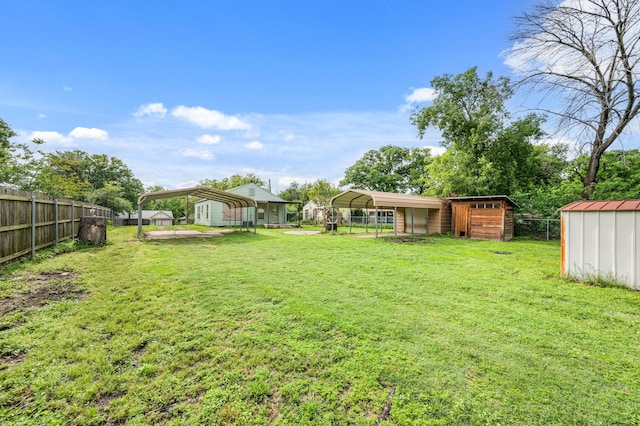 view of yard featuring fence, an outbuilding, a detached carport, and a storage unit