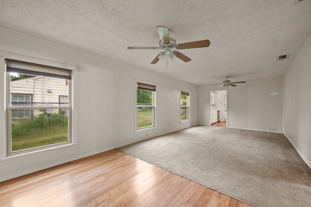 unfurnished living room with a textured ceiling, ceiling fan, visible vents, and wood finished floors