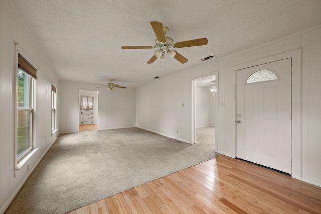 entrance foyer featuring crown molding, ceiling fan, a textured ceiling, light wood-type flooring, and visible vents