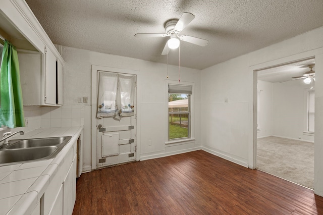 kitchen featuring dark wood-style flooring, tile counters, ceiling fan, and a textured ceiling