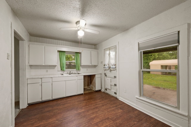 kitchen with ceiling fan, dark wood-style flooring, a sink, white cabinets, and tile counters