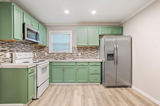 kitchen with crown molding, light wood-style floors, light countertops, a sink, and stainless steel appliances