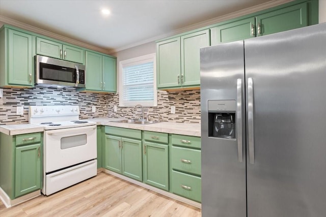 kitchen with crown molding, light countertops, green cabinetry, a sink, and stainless steel appliances