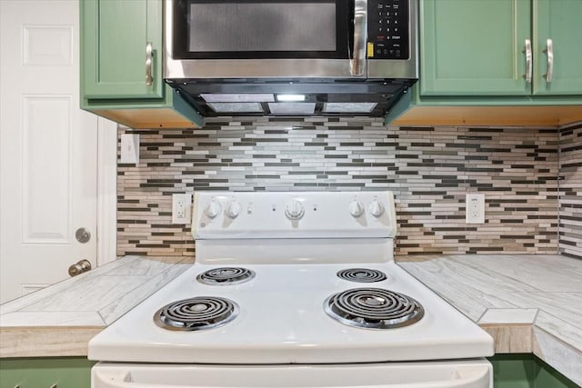 kitchen featuring light countertops, stainless steel microwave, white range with electric stovetop, tasteful backsplash, and green cabinets