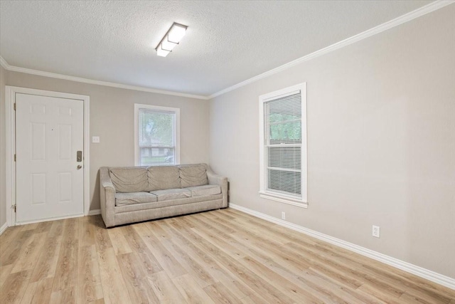 living room with crown molding, a textured ceiling, light wood finished floors, and baseboards