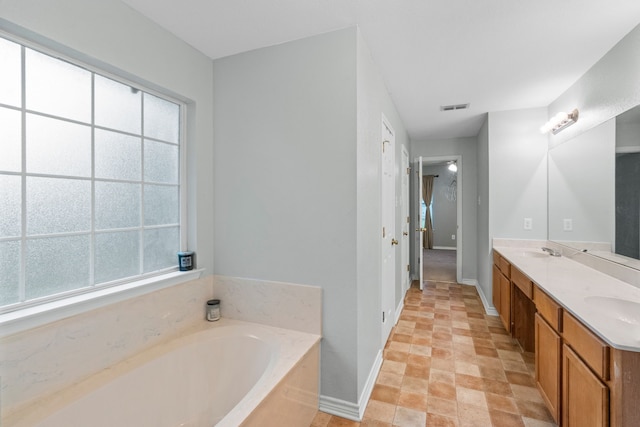 full bathroom with baseboards, a sink, a wealth of natural light, and a bath