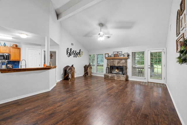 unfurnished living room with a stone fireplace, wood finished floors, a healthy amount of sunlight, and high vaulted ceiling